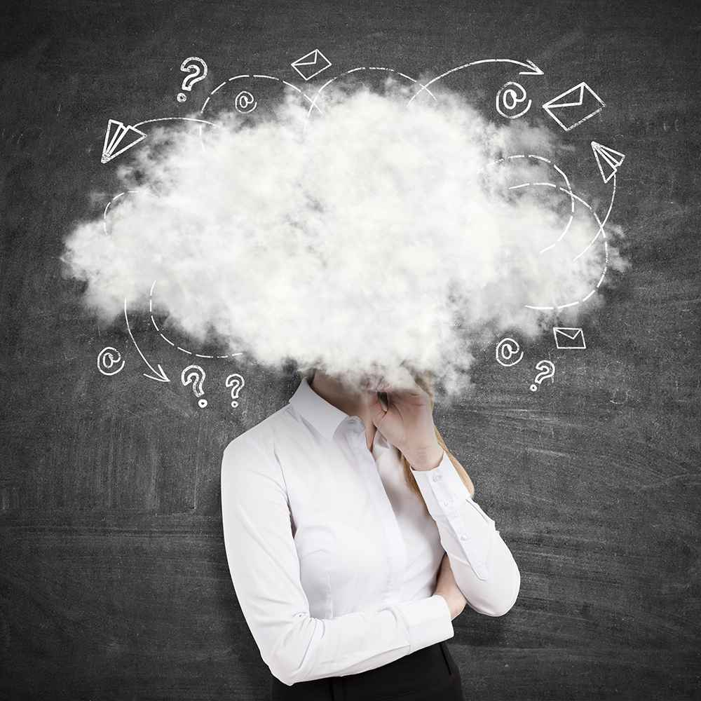 Side view of young businesswoman with head in the clouds on chalkboard background. Writer's block concept