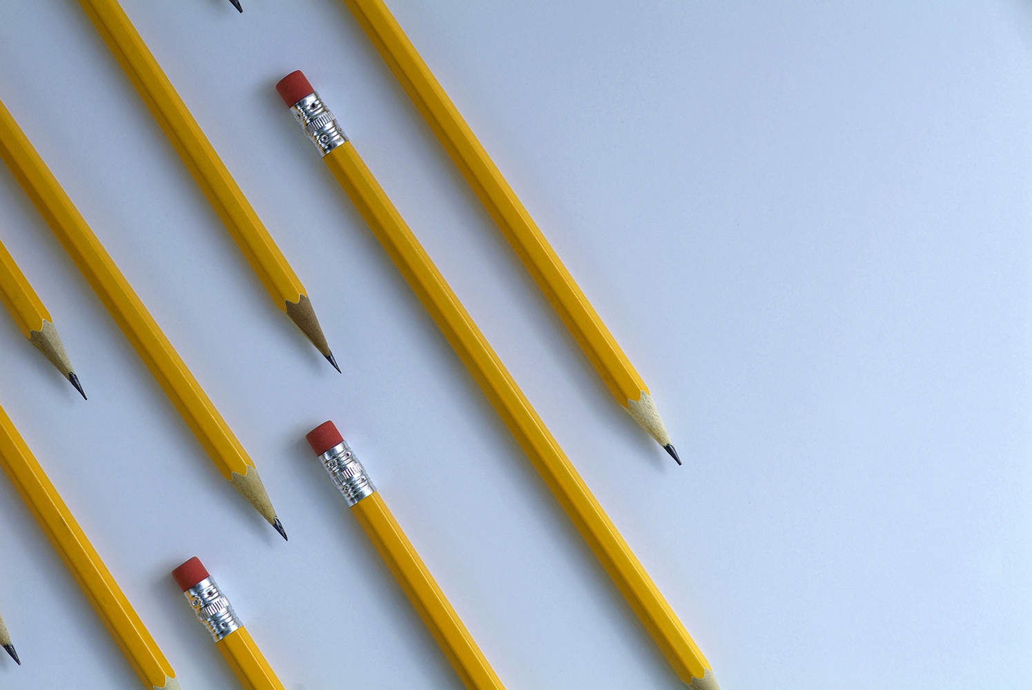 Several yellow pencils on diagonal and parallel to each other on white