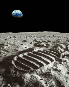 Footprint of astronaut on the moon with earth above the horizon.